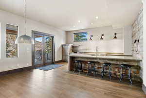 Indoor wet bar with open shelves, hanging light fixtures, light wood-style flooring, recessed lighting, and freestanding refrigerator