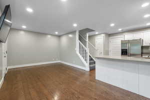 Kitchen with stainless steel fridge with ice dispenser, recessed lighting, white cabinetry, dark wood-type flooring, and light stone countertops