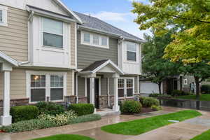 Craftsman-style house with stone siding, roof with shingles, and board and batten siding