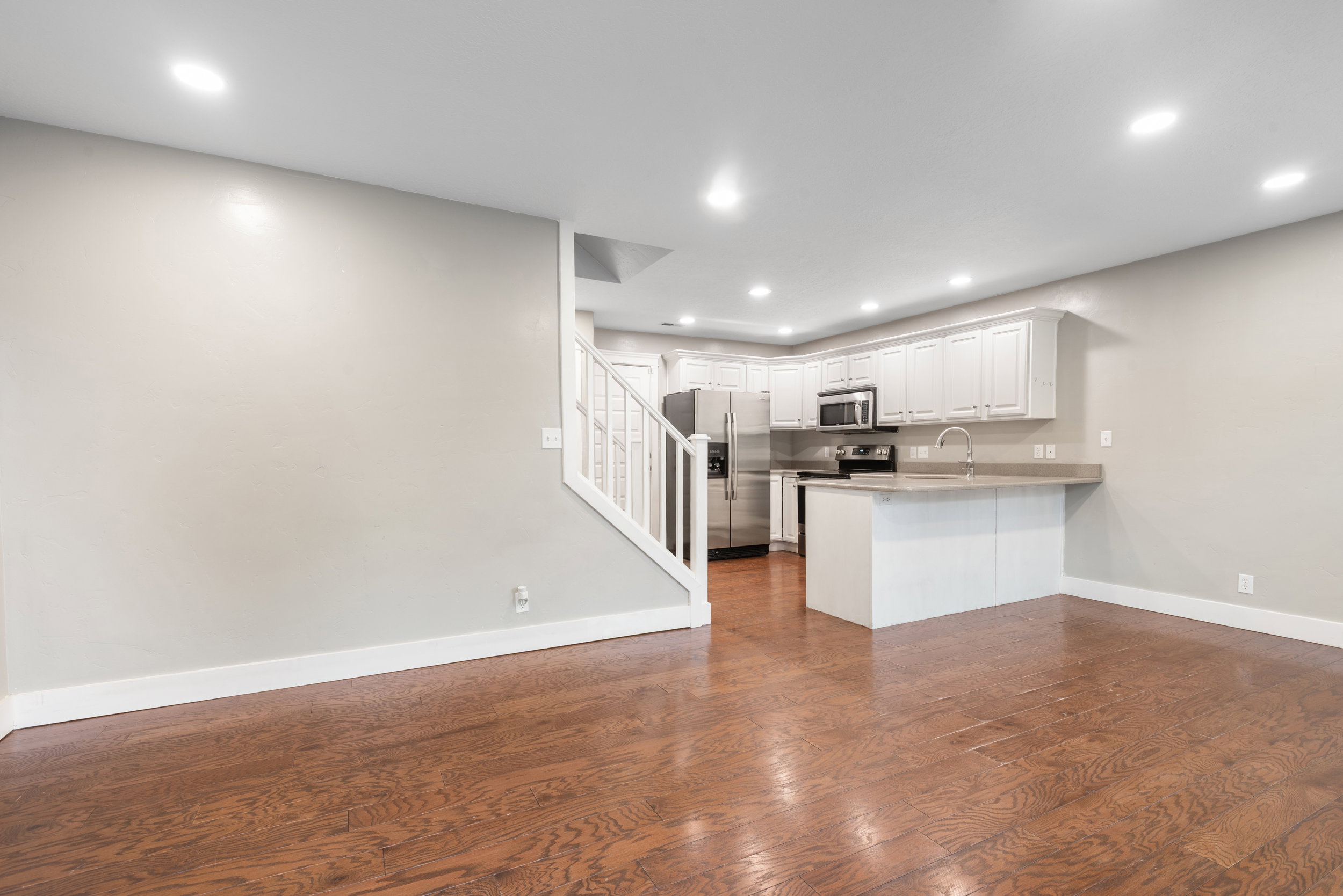 Kitchen featuring stainless steel appliances, a peninsula, white cabinets, dark wood finished floors, and recessed lighting