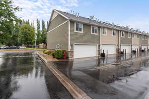 Rear view of house featuring a garage, a shingled roof, board and batten siding, and a residential view