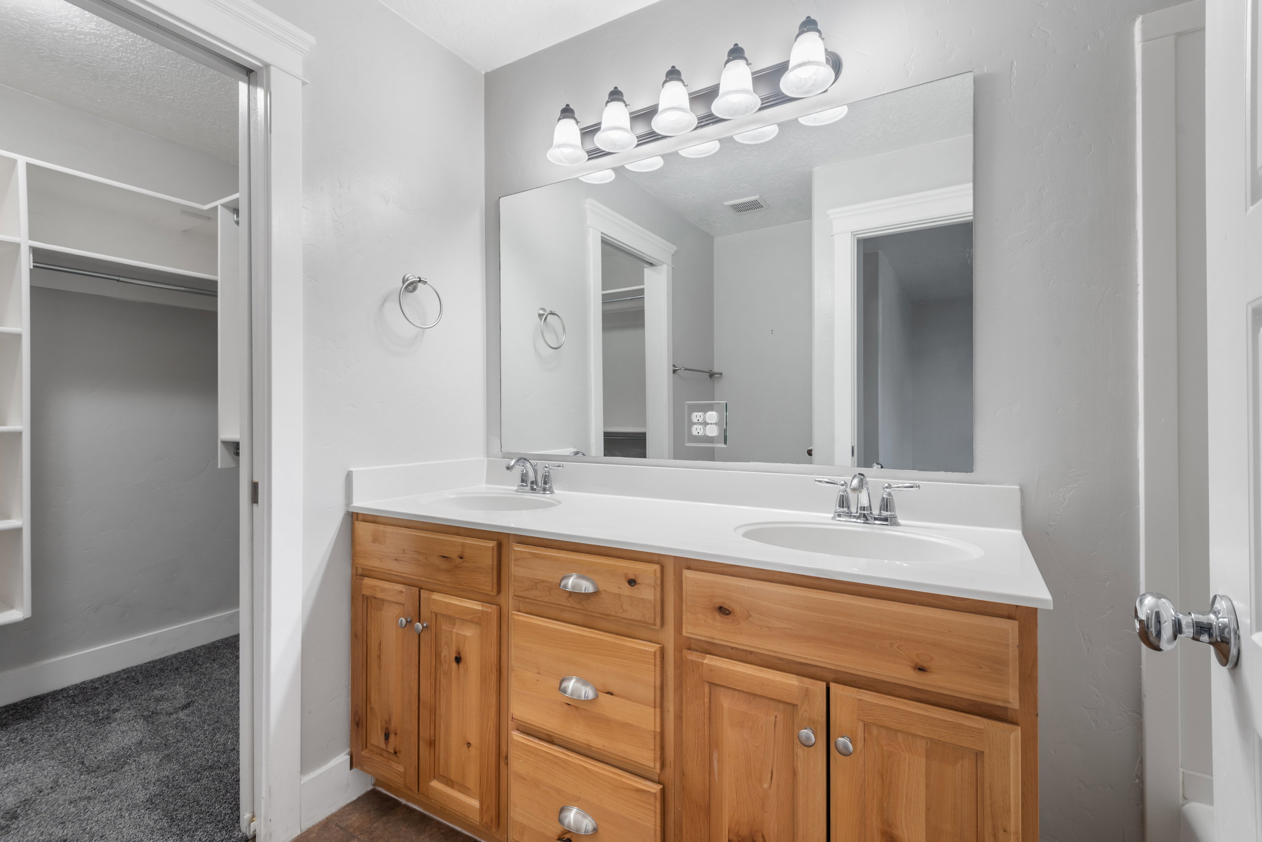 Bathroom with double vanity and a walk in closet