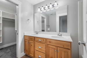 Bathroom with double vanity and a walk in closet