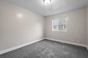 Carpeted empty room with baseboards and a textured ceiling