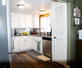 Kitchen with white cabinetry, stainless steel appliances, dark wood-style floors, and dark stone counters