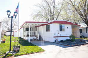 Manufactured / mobile home featuring a front lawn, an attached carport, and concrete driveway