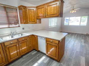 Kitchen featuring a peninsula, light countertops, wood finish cabinets, ceiling fan, and dark wood finished floors