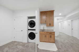 Laundry closet and wet bar area featuring light carpet, stacked washer and dryer, and recessed lighting