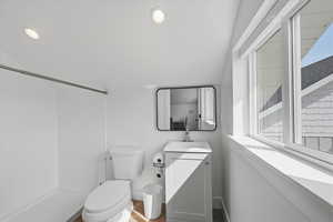Studio aparment bathroom with vanity, healthy amount of natural light, lofted ceiling, and a shower