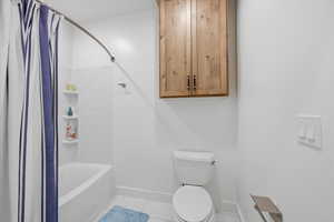 Downstairs full bathroom featuring shower / tub combo with curtain and light tile patterned floors