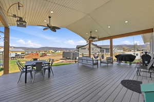 Deck with a ceiling fan, a mountain view, an outdoor living / dining area, and a yard