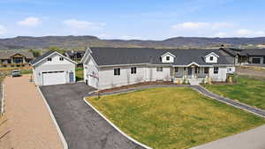 Modern inspired farmhouse featuring a mountain view, covered porch, a front yard, and asphalt driveway