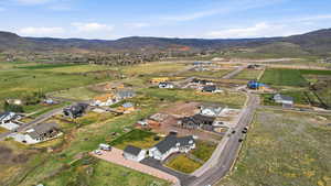 Aerial view of property and surrounding area featuring mountains, nearby suburban area, and rural landscape