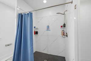 Primary bathroom with a marble finish shower and recessed lighting