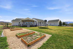 Rear view of property with a mountain view, a trampoline, a garden, a lawn, and covered porch