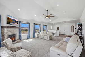 Living area featuring a fireplace, light carpet, lofted ceiling, ceiling fan, and recessed lighting