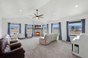 Carpeted living room featuring a brick fireplace, lofted ceiling, ceiling fan, and recessed lighting