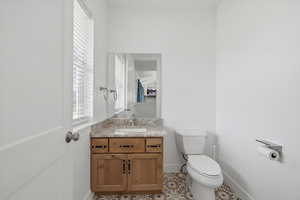 Half bathroom with vanity, light tile patterned floors, and plenty of natural light