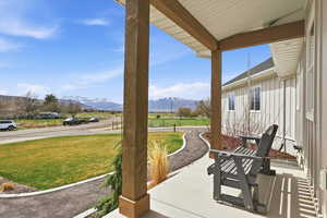 Covered front porch featuring a mountain view, a lawn, and a rural view