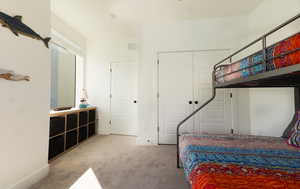Bedroom with light carpet and a closet