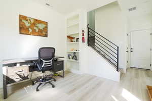 Office space featuring light wood-style floors and built in features