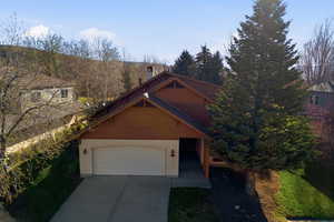 View of front facade featuring concrete driveway, a chimney, and an attached garage