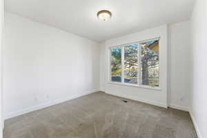 Spare room featuring light colored carpet and baseboards