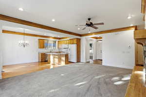 Kitchen featuring open floor plan, light carpet, white appliances, hanging lights, and light countertops