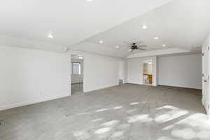 Unfurnished living room with a tray ceiling, a ceiling fan, light colored carpet, and recessed lighting