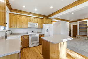 Kitchen with white appliances, a center island, crown molding, light wood-style floors, and recessed lighting