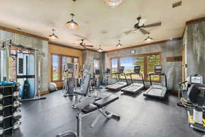 Workout area featuring wallpapered walls, crown molding, and ceiling fan