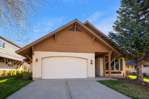 View of front of house featuring concrete driveway, an attached garage, a front yard, and stucco siding