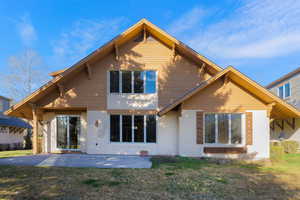 Rear view of property with a yard, stucco siding, and a patio