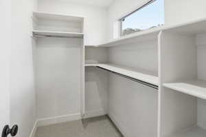 Walk in closet featuring light colored carpet