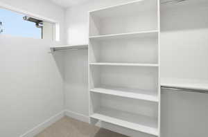 Walk in closet with light colored carpet