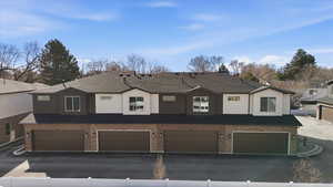 View of front of property with an attached garage, stucco siding, and brick siding