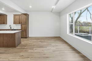 Kitchen featuring wood finish cabinetry, light stone counters, light wood-style flooring, and recessed lighting