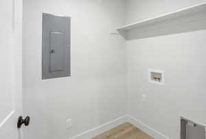 Laundry room with light wood-type flooring, electric panel, and hookup for a washing machine