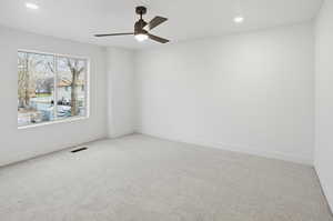 Empty room with light colored carpet, a ceiling fan, and recessed lighting