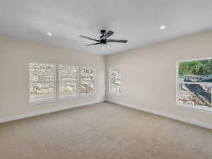 Empty room featuring light carpet, a ceiling fan, plenty of natural light, and recessed lighting