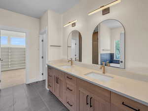 Full bath with plenty of natural light, double vanity, dark tile patterned flooring, and dark carpet