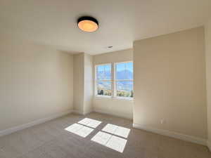 Spare room featuring a mountain view and light carpet