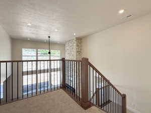 Corridor featuring carpet, a textured ceiling, recessed lighting, and an upstairs landing