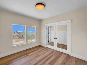 Unfurnished bedroom featuring french doors, light wood finished floors, and a closet