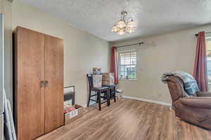 Living area with a chandelier, light wood-style floors, and a textured ceiling