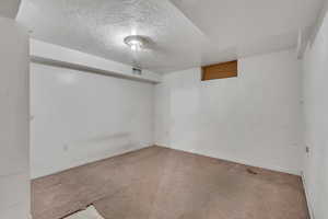 Empty room with a textured ceiling and baseboards