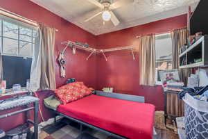 Bedroom featuring a ceiling fan, a textured ceiling, and tile patterned floors