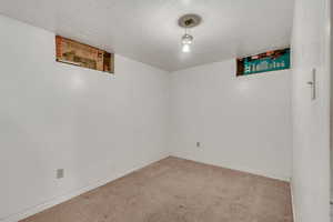 Carpeted empty room featuring a textured ceiling and baseboards