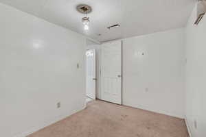 Spare room featuring a textured ceiling and light colored carpet