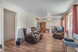 Living area with a chandelier, wood finished floors, and a textured ceiling